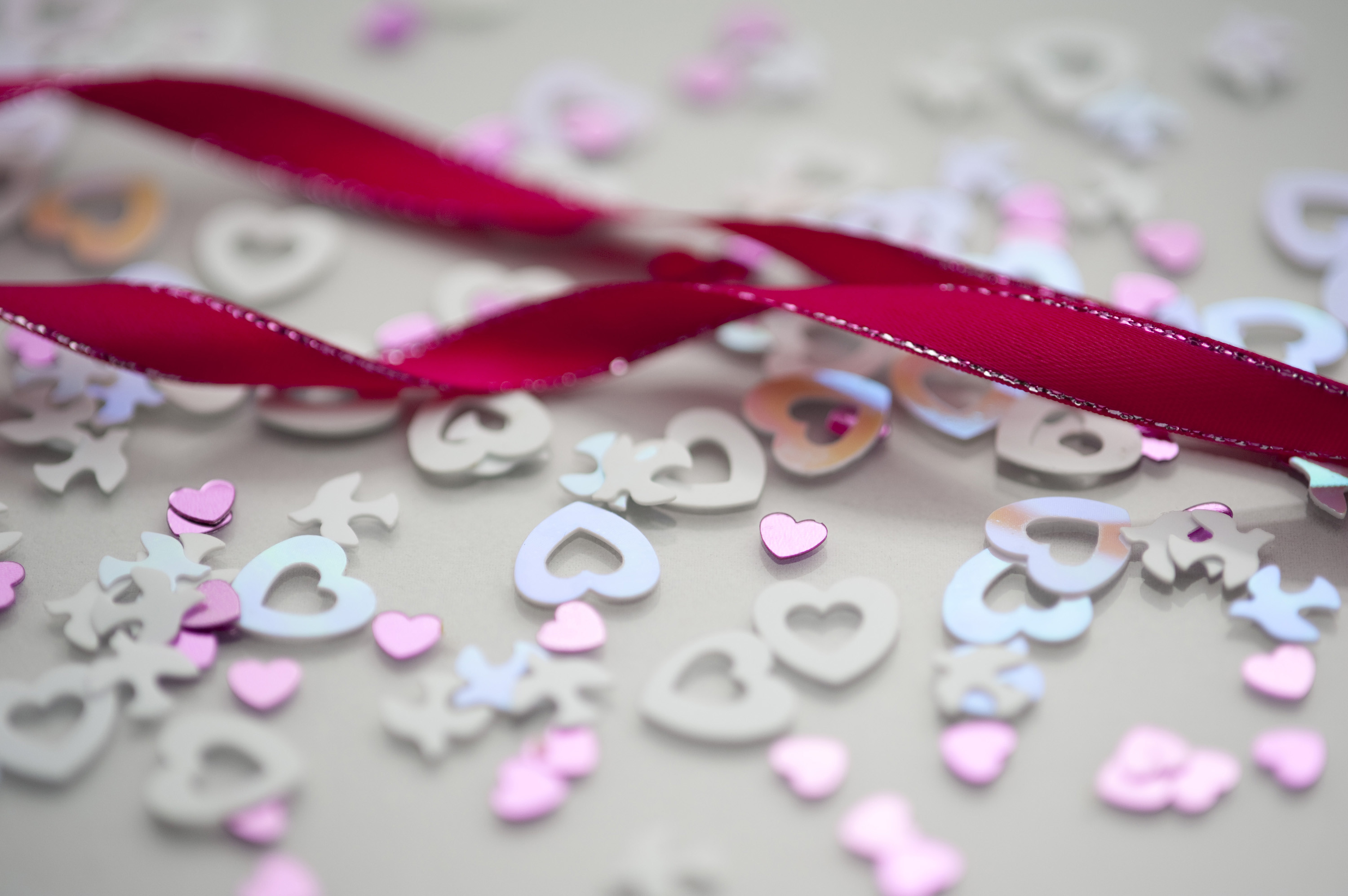 A Background Image Of Pink Twisted Ribbon And Wedding Confetti Shapes 3000x1996